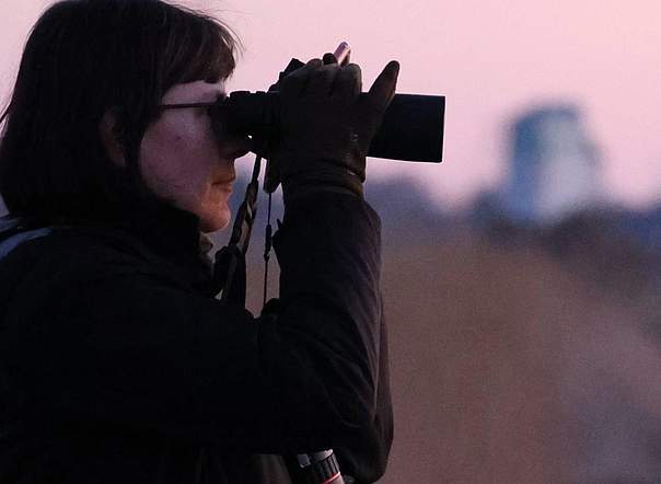 "Rebhuhn retten - Vielfalt fördern!": Kartiererin mit Fernglas. Bild: Karina Dreyer